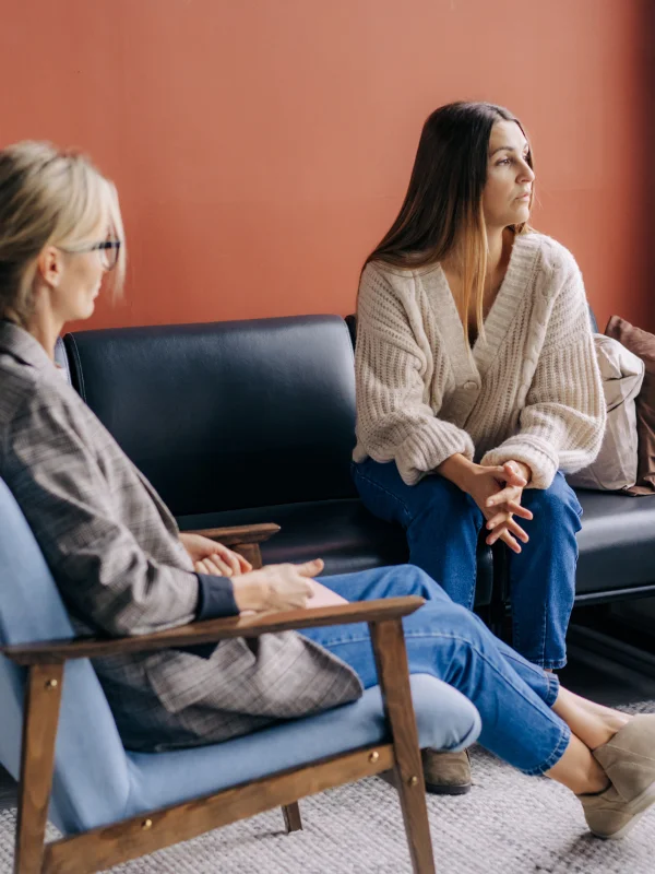 A young woman stares out the window while listening to her therapist.